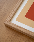 all-groups - Close-up of an oak frame corner on a wooden surface, showing the peach border and part of the terracotta block of the Stamnos print.